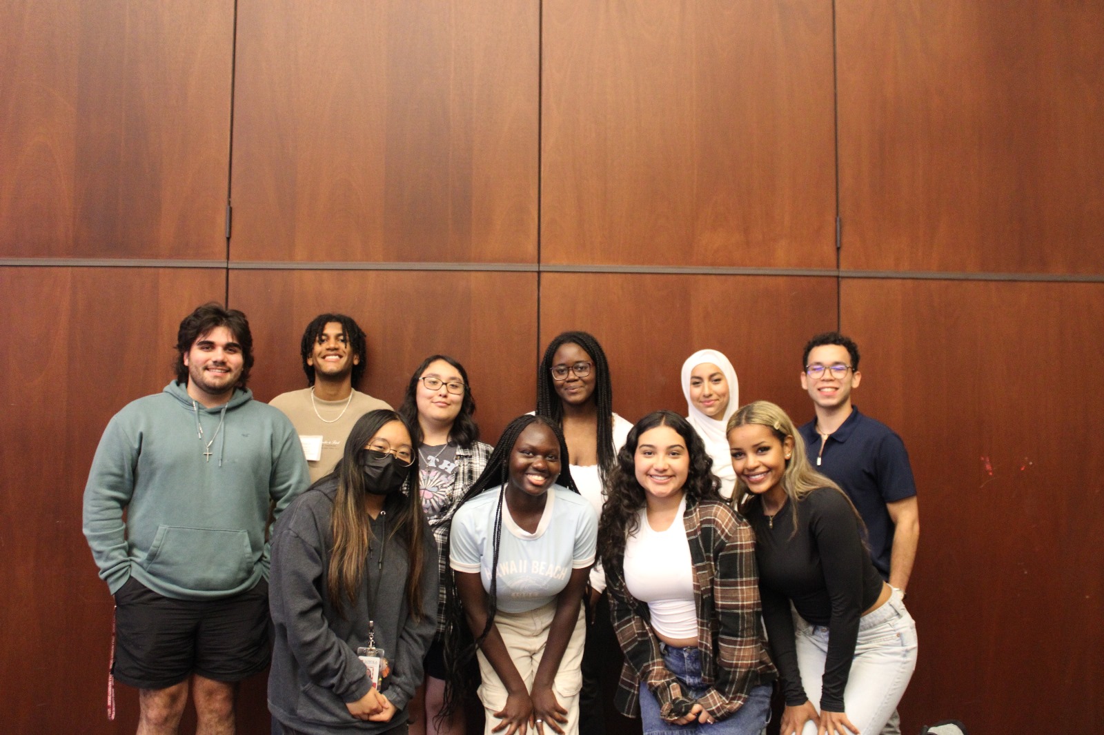 Loyola University Chicago Leadership Scholars Program Fall 2024 Cohort is in the Damen Student Center at the Lake Shore Campus. They are standing in two lines facing the camera and smiling.